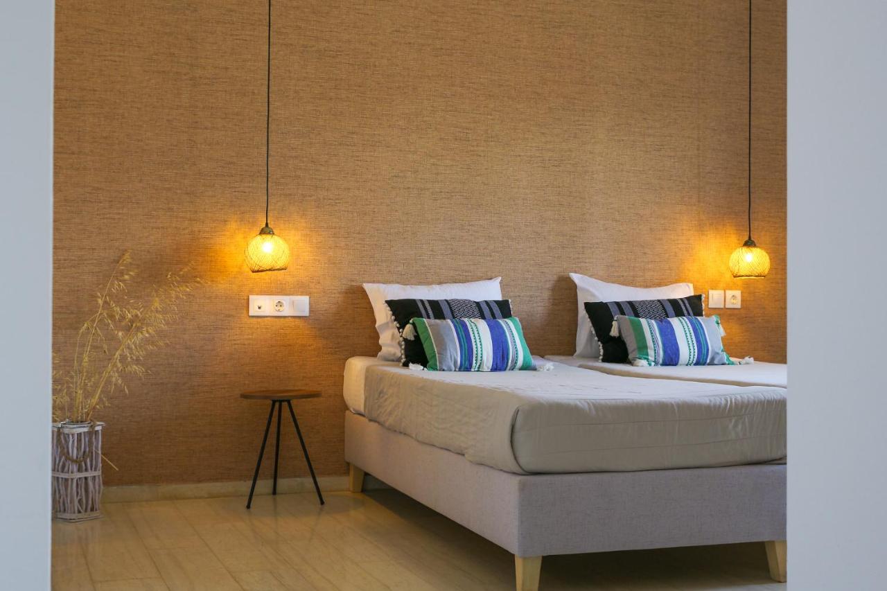 een slaapkamer met twee bedden en twee lampen aan de muur bij Anemos Inn by Estia in Kokkíni Khánion