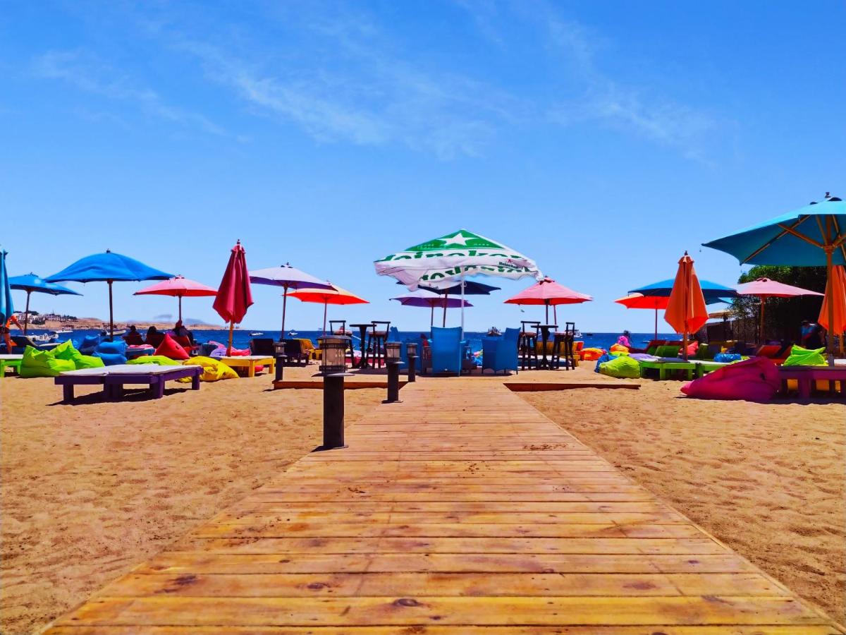 een houten loopbrug op een strand met parasols bij Naama Blue Hotel in Sharm El Sheikh