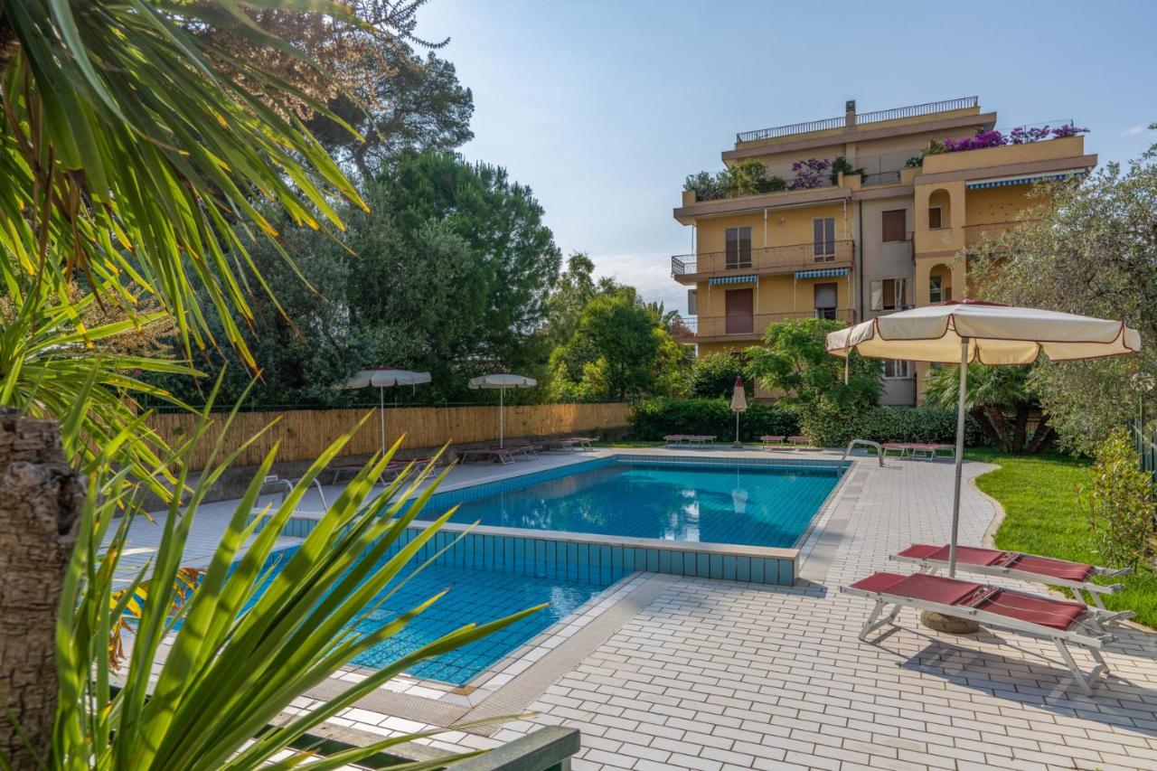 een zwembad met twee ligstoelen en een parasol bij Hotel Garden in Alassio +36 foto's