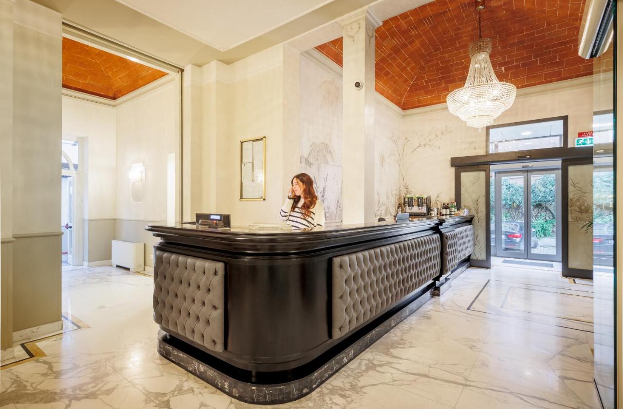 een vrouw zit aan de bar in een grote kamer bij Hotel Embassy in Florence