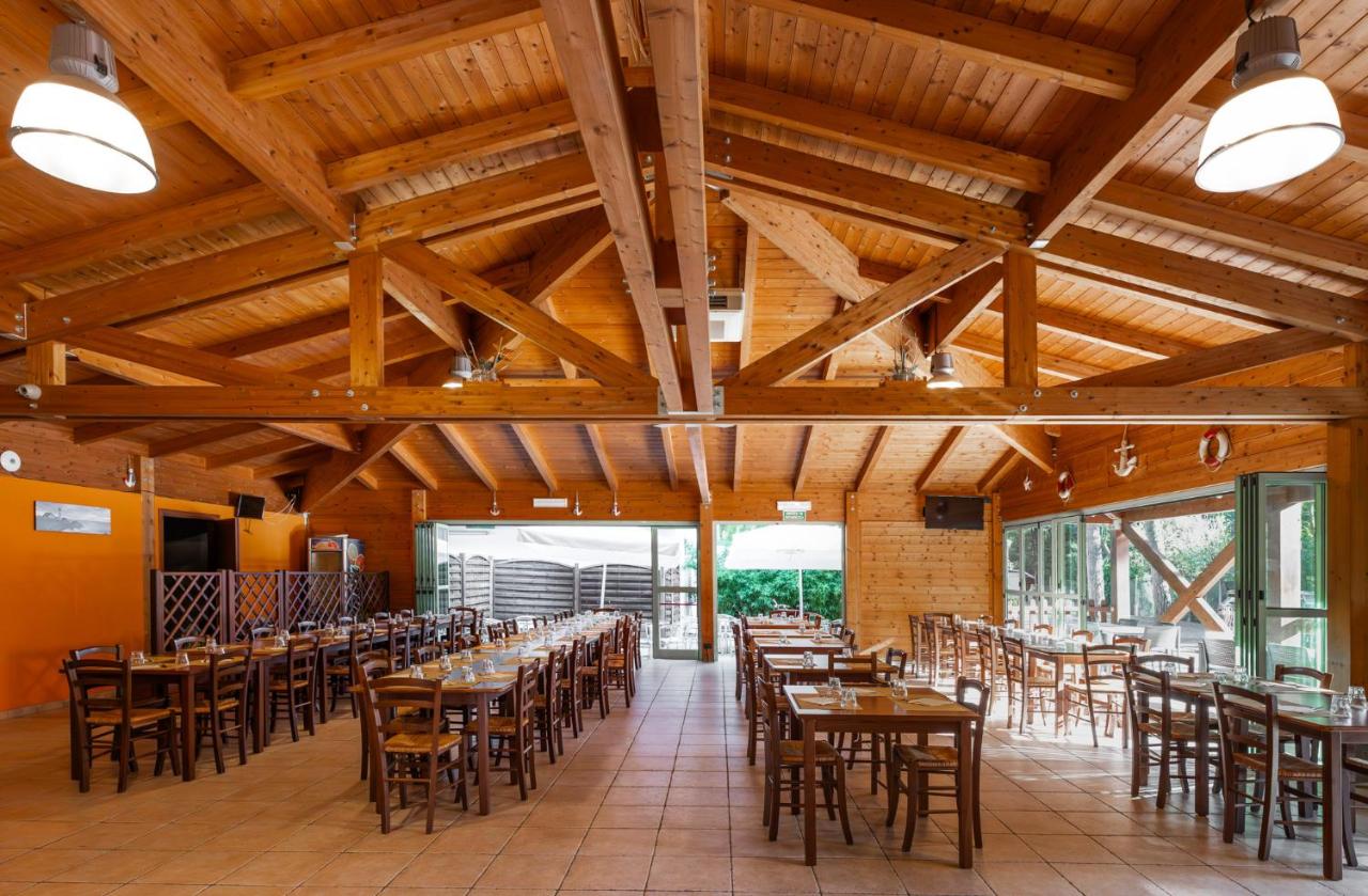 een eetzaal met tafels en stoelen in een gebouw bij Club del Sole Rivaverde Easy Camping Village in Marina di Ravenna +9