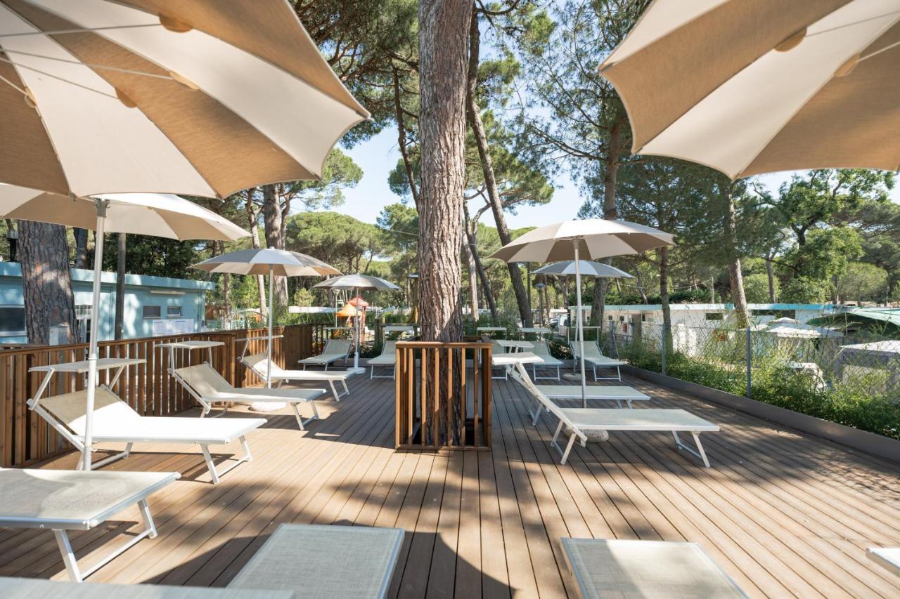 een terras met tafels, stoelen en parasols bij Club del Sole Rivaverde Easy Camping Village in Marina di Ravenna