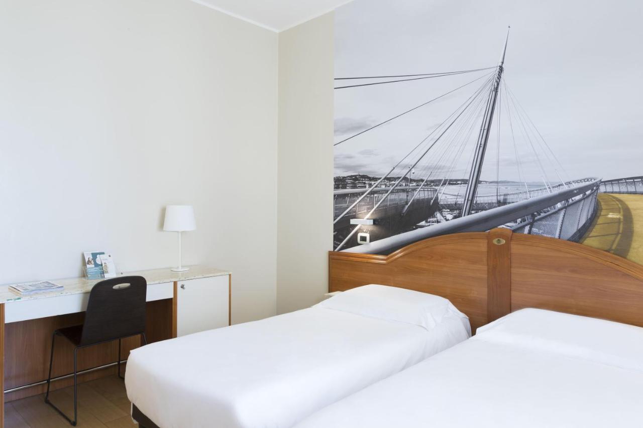 een hotelkamer met twee bedden en een bureau en een boot bij B&B Hotel Pescara in Pescara