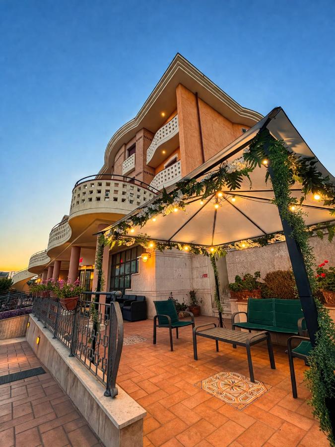 een terras met banken en een parasol voor een gebouw bij Hotel Valle Rossa in San Giovanni Rotondo