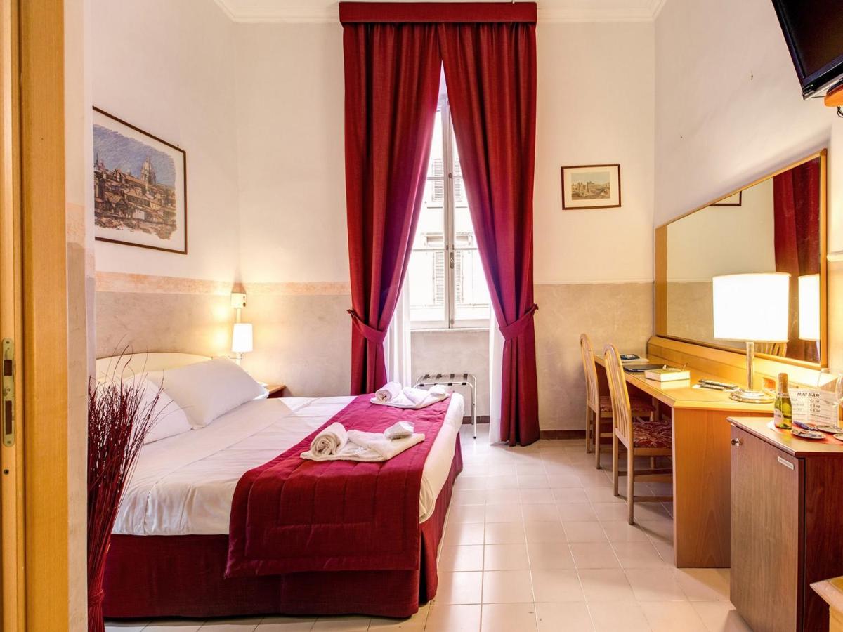 een slaapkamer met een bed met rode gordijnen en een bureau bij Hotel Giotto Flavia in Rome