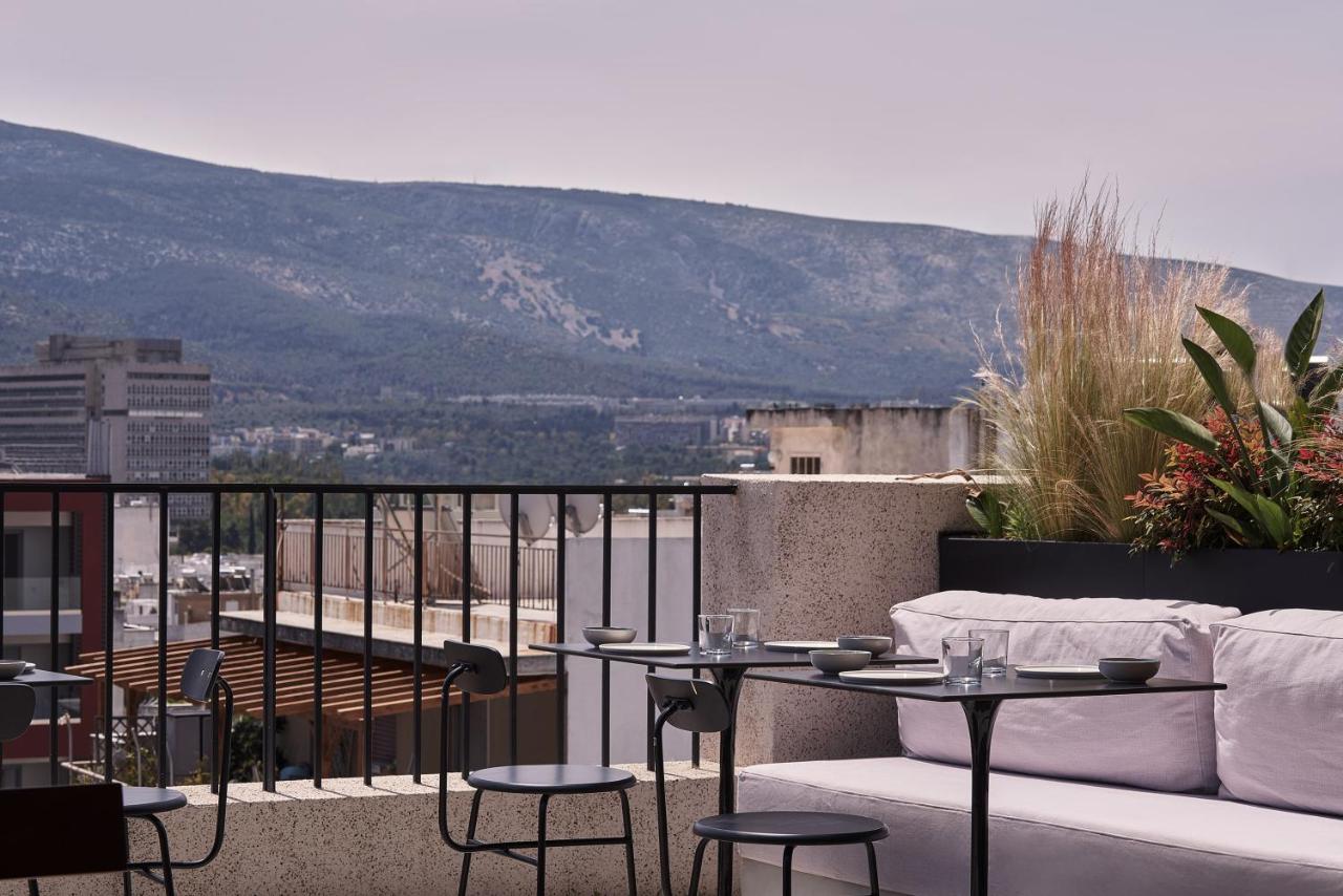 een balkon met een bank, tafels en stoelen bij The Newel Psychiko in Athene