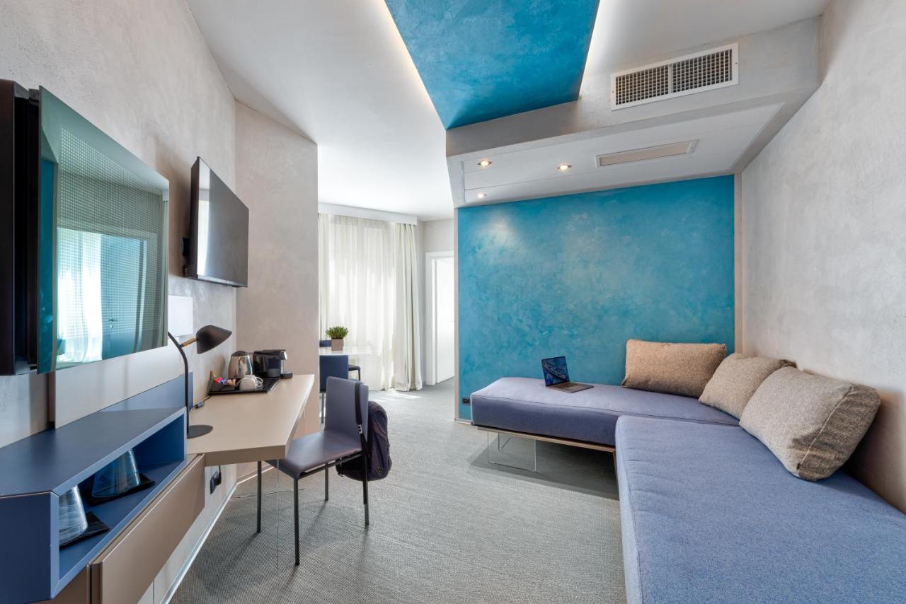 een woonkamer met een blauwe accentmuur en een bank bij Carrick Hotel Camogli Portofino Coast in Camogli