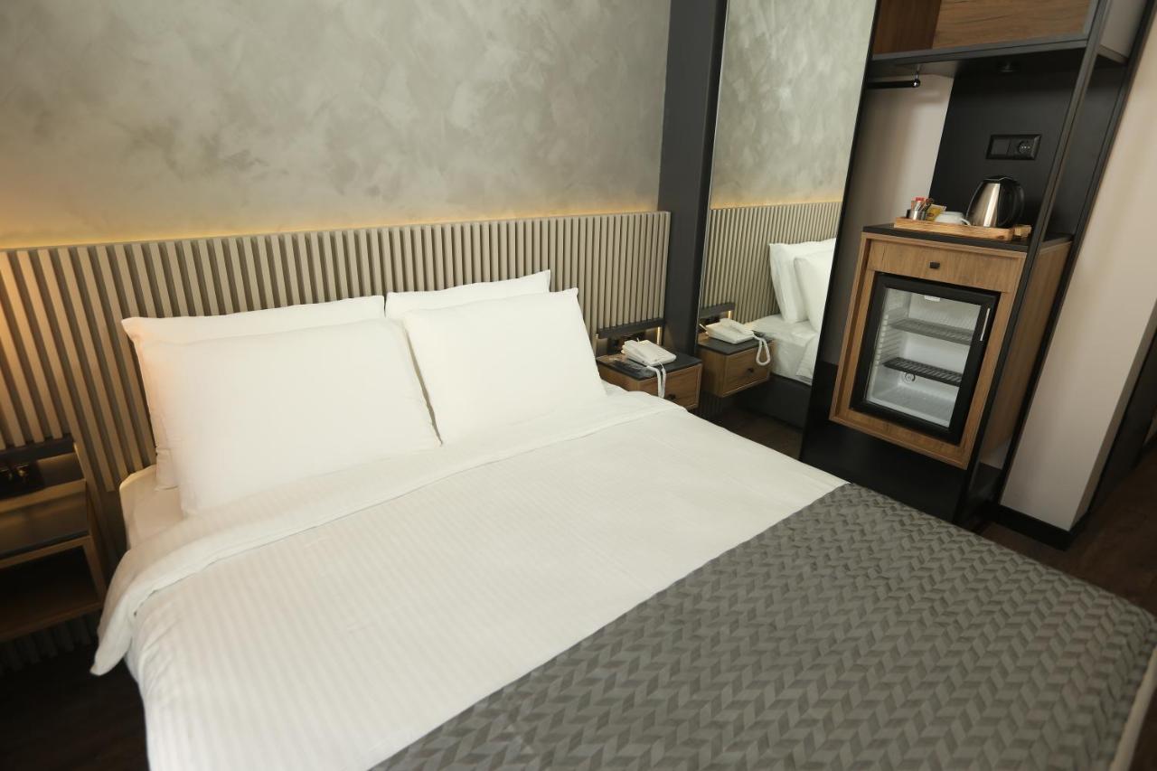 een slaapkamer met een groot bed met witte lakens bij Moja City Hotel in Istanbul