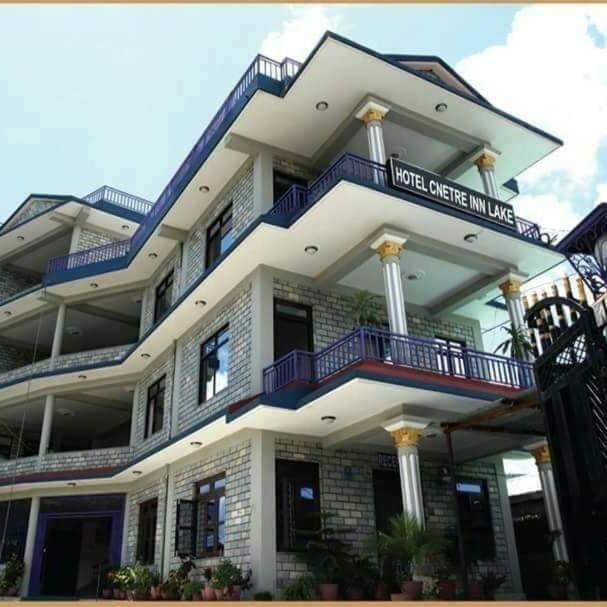 een groot wit gebouw met blauwe balkons bij Hotel Center Inn Lake in Pokhara
