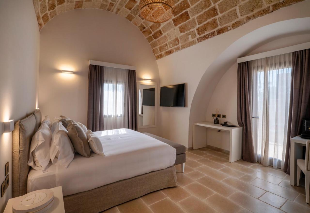 een slaapkamer met een groot bed en een bakstenen muur bij Masseria Corsano in Nardò