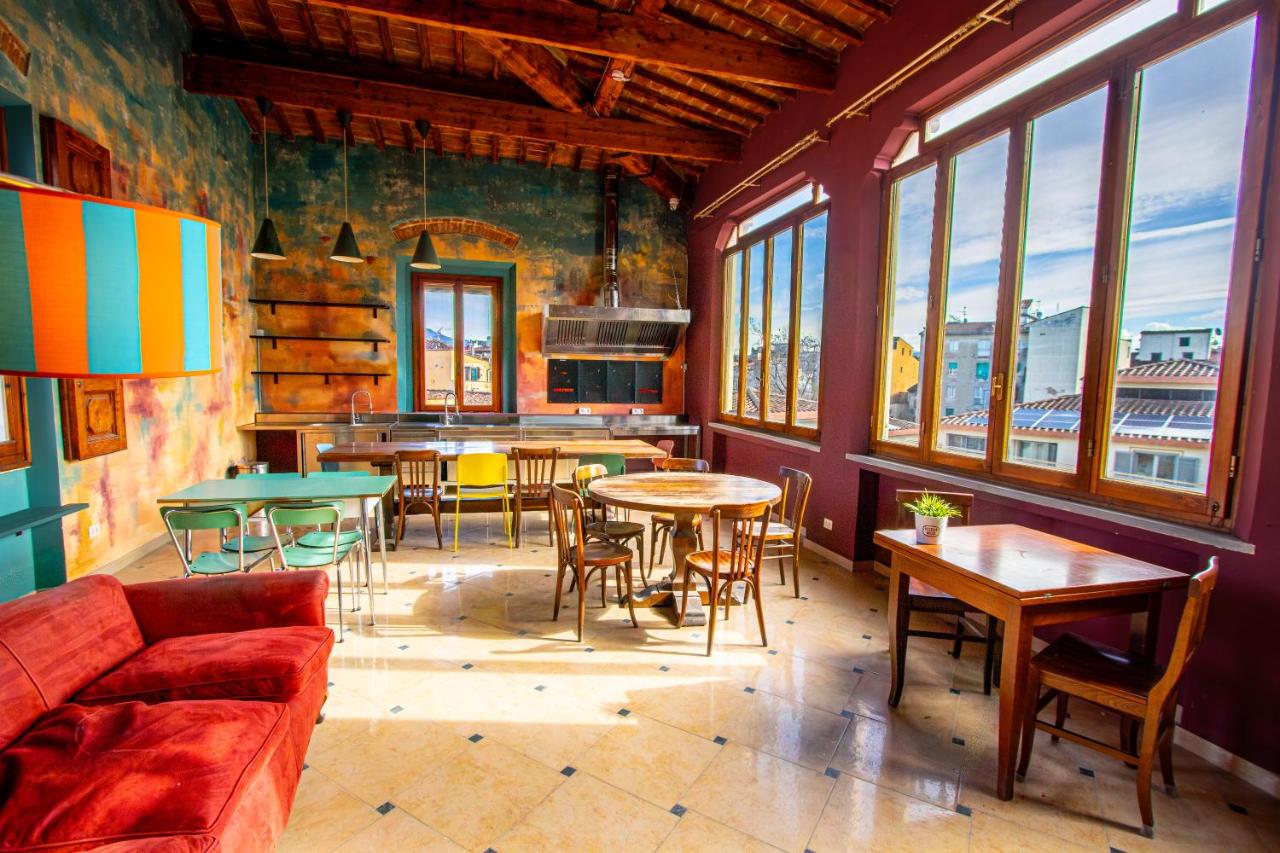 een woonkamer met tafels en stoelen en ramen bij Ostello Bello Firenze in Florence