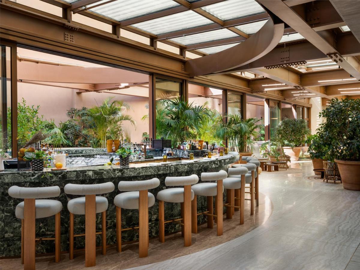 een lobby met een bar met barkrukken en planten bij Six Senses Rome in Rome
