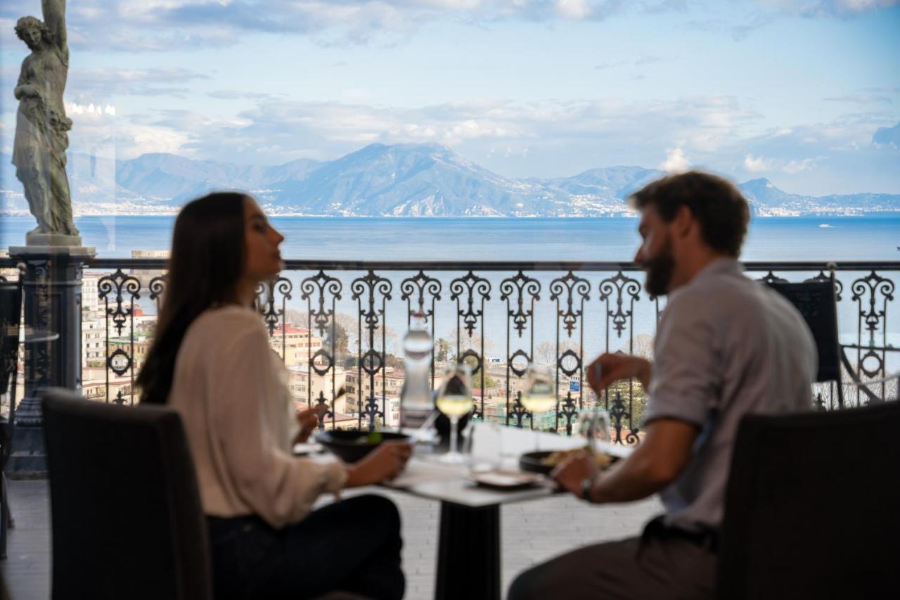 Twee mensen zitten aan een tafel met uitzicht op de oceaan. bij Grand Hotel Parker's in Napels