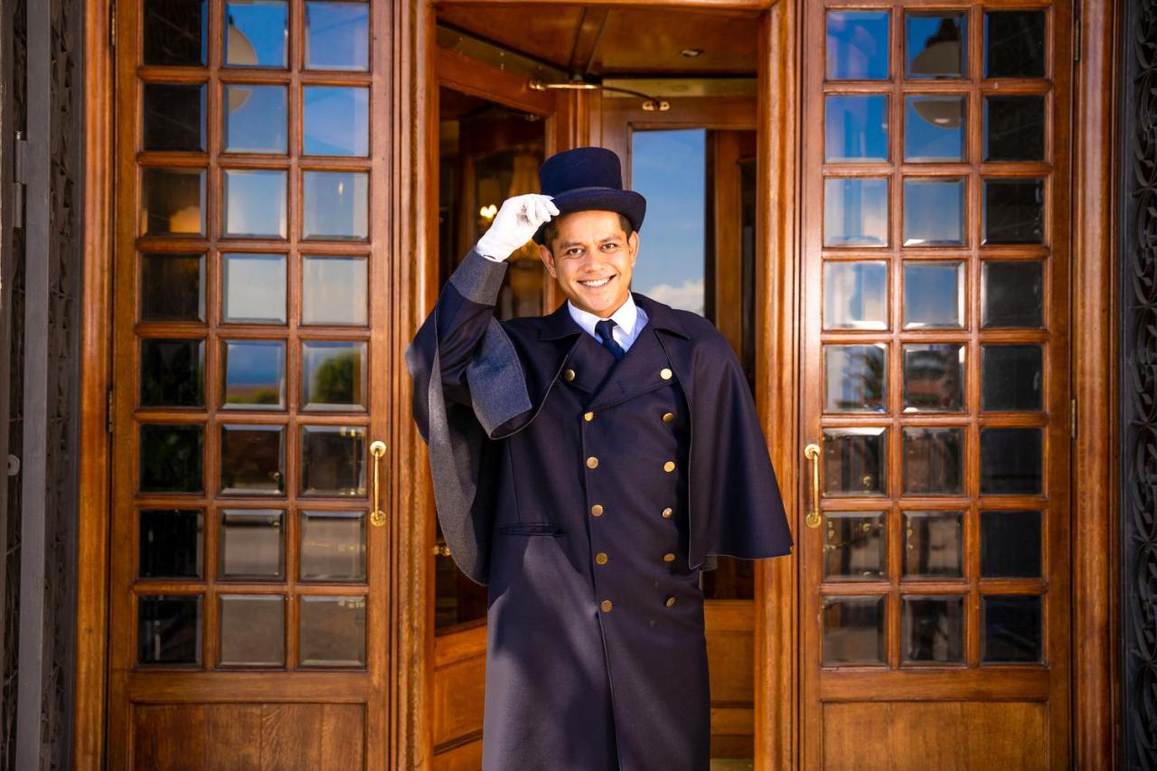 een man in een afstudeeruniform staat voor een deur bij Grand Hotel Parker's in Napels