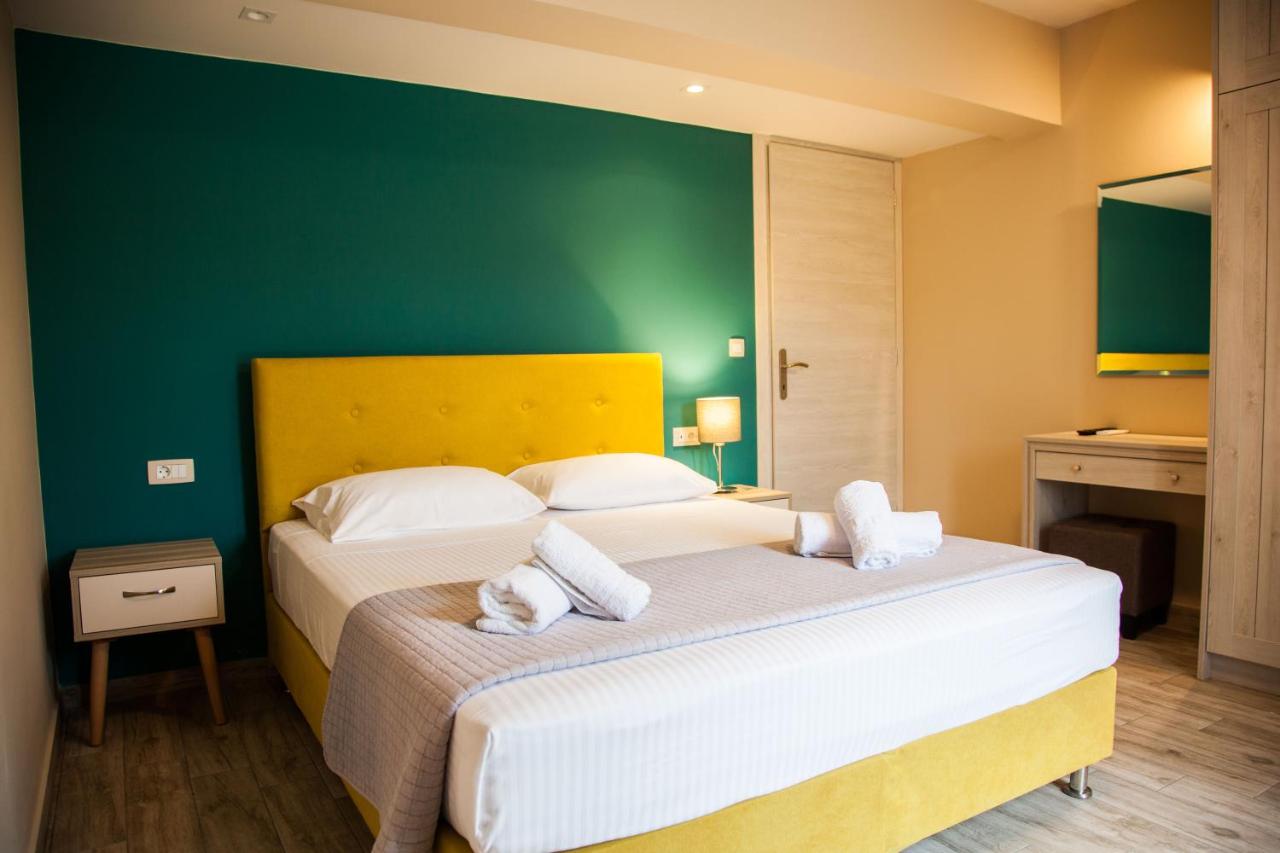 een slaapkamer met twee bedden en een groene muur bij Paporas Apartments in Svoronata