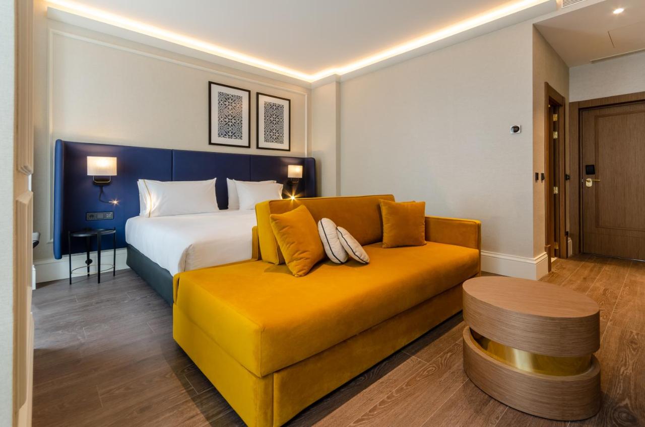 een slaapkamer met een bed en een gele bank bij Eurostars Lisboa Baixa in Lissabon