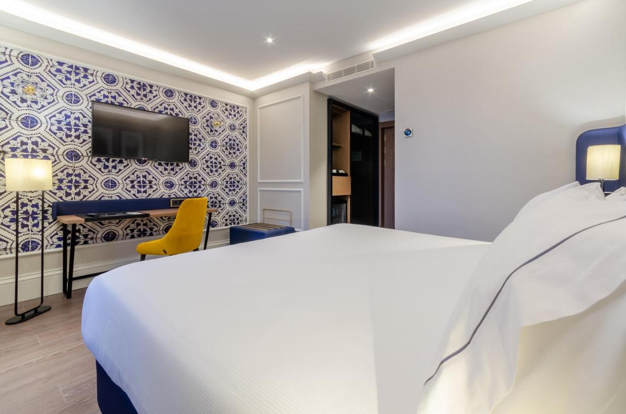 een hotelkamer met een wit bed en een tv bij Eurostars Lisboa Baixa in Lissabon