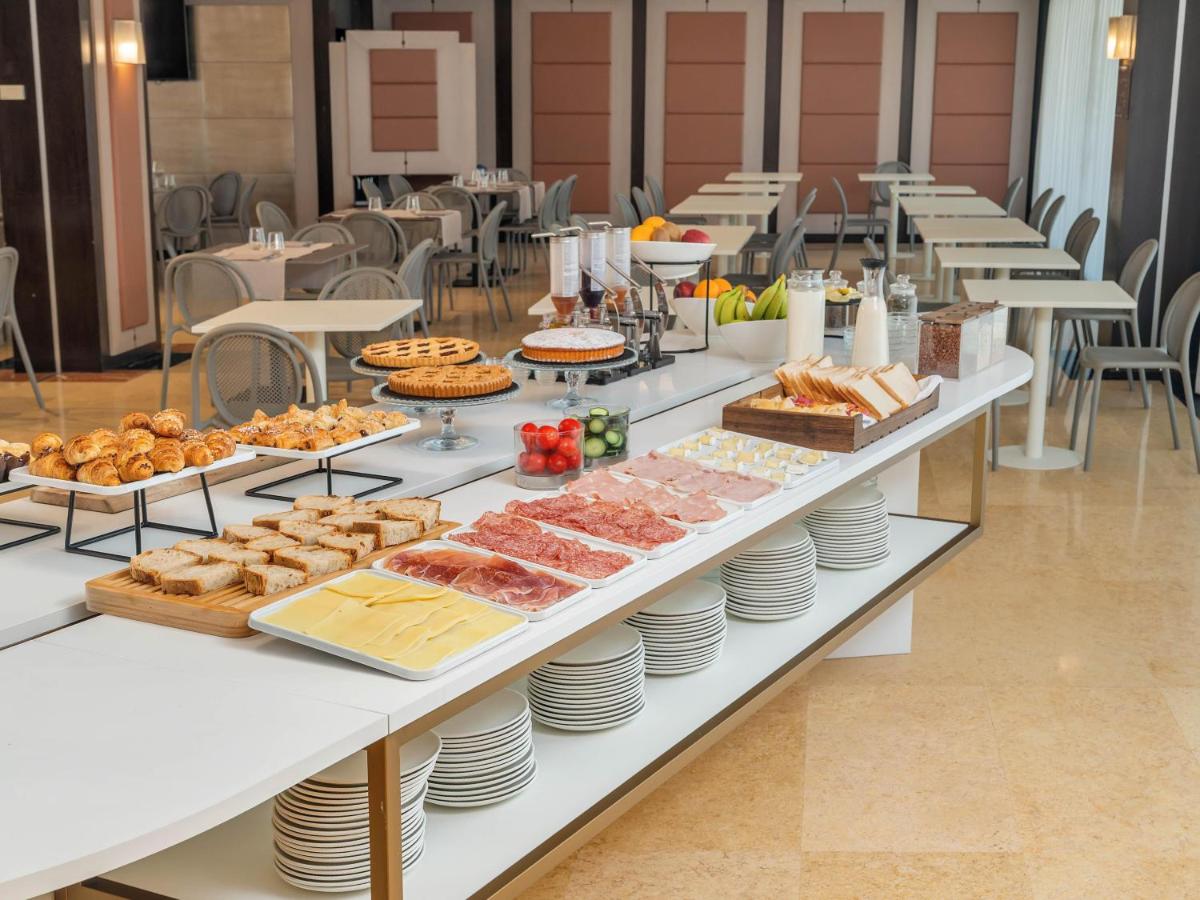 Een buffet met eten op een tafel, met borden en gebak. bij B&B HOTEL Napoli San Mauro in Casalnuovo di Napoli