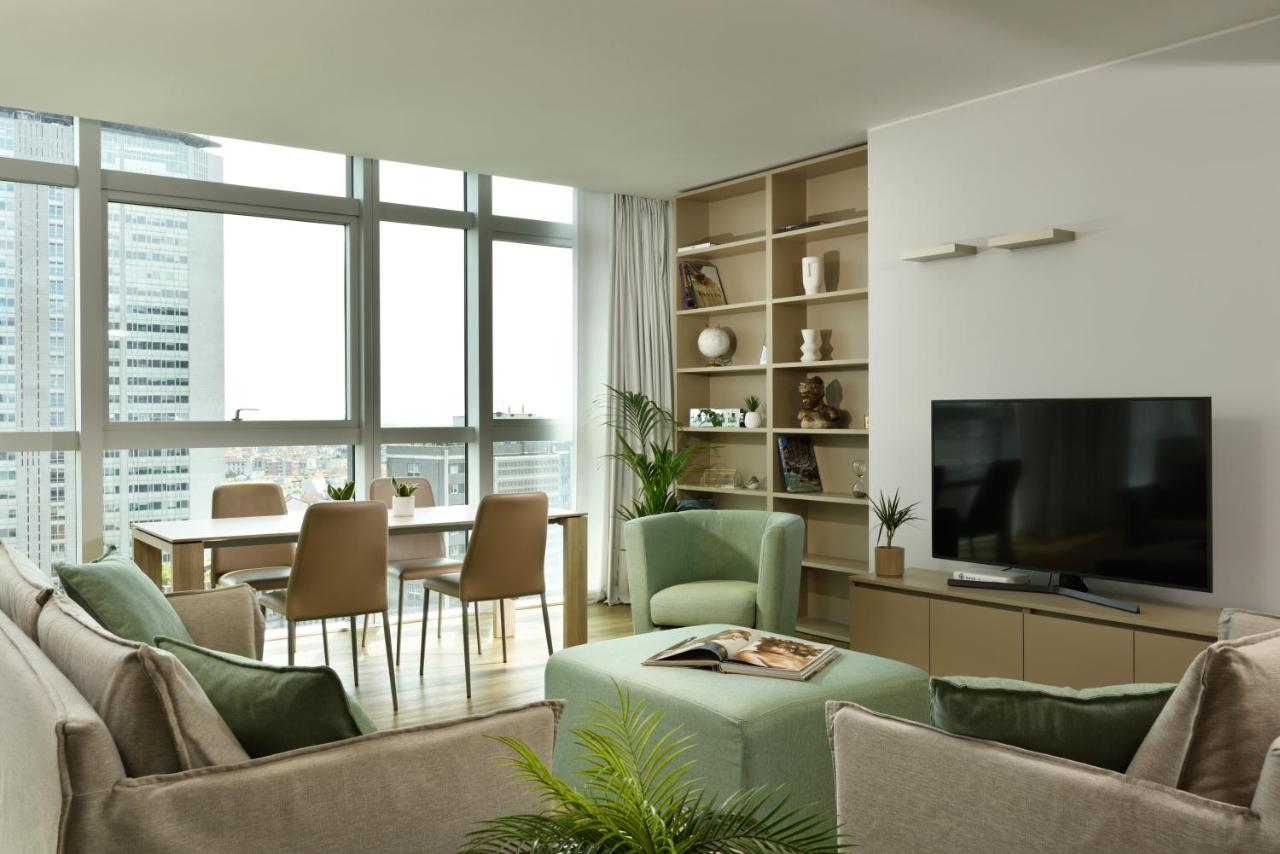 een woonkamer met een televisie, een tafel en stoelen bij Torre Galfa Milano Luxury Apartments | UNA Esperienze in Milaa