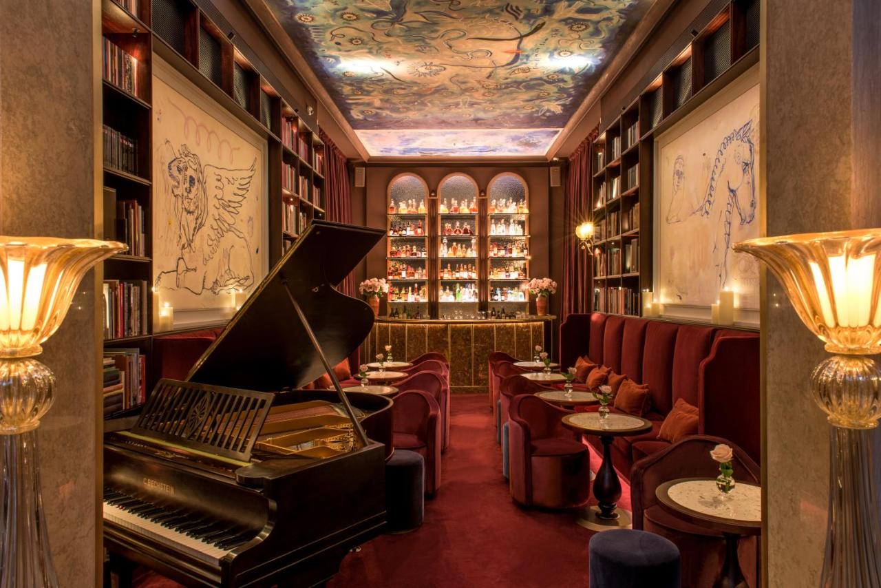 een bibliotheek met een piano in een kamer met tafels en stoelen bij Nolinski Venezia - Evok Collection in Venetië