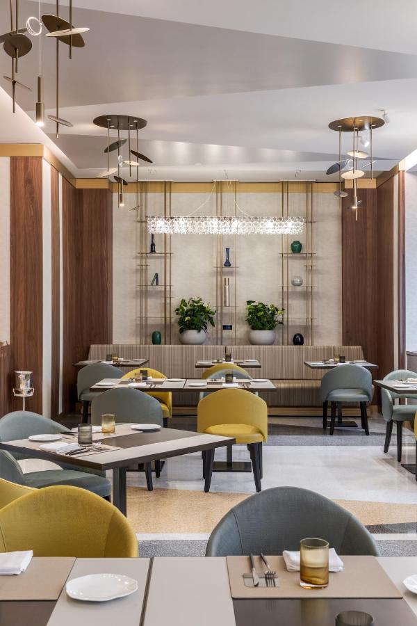 een restaurant met tafels en stoelen en een kroonluchter bij Casa Baglioni Milan - The Leading Hotels of the World in Mi
