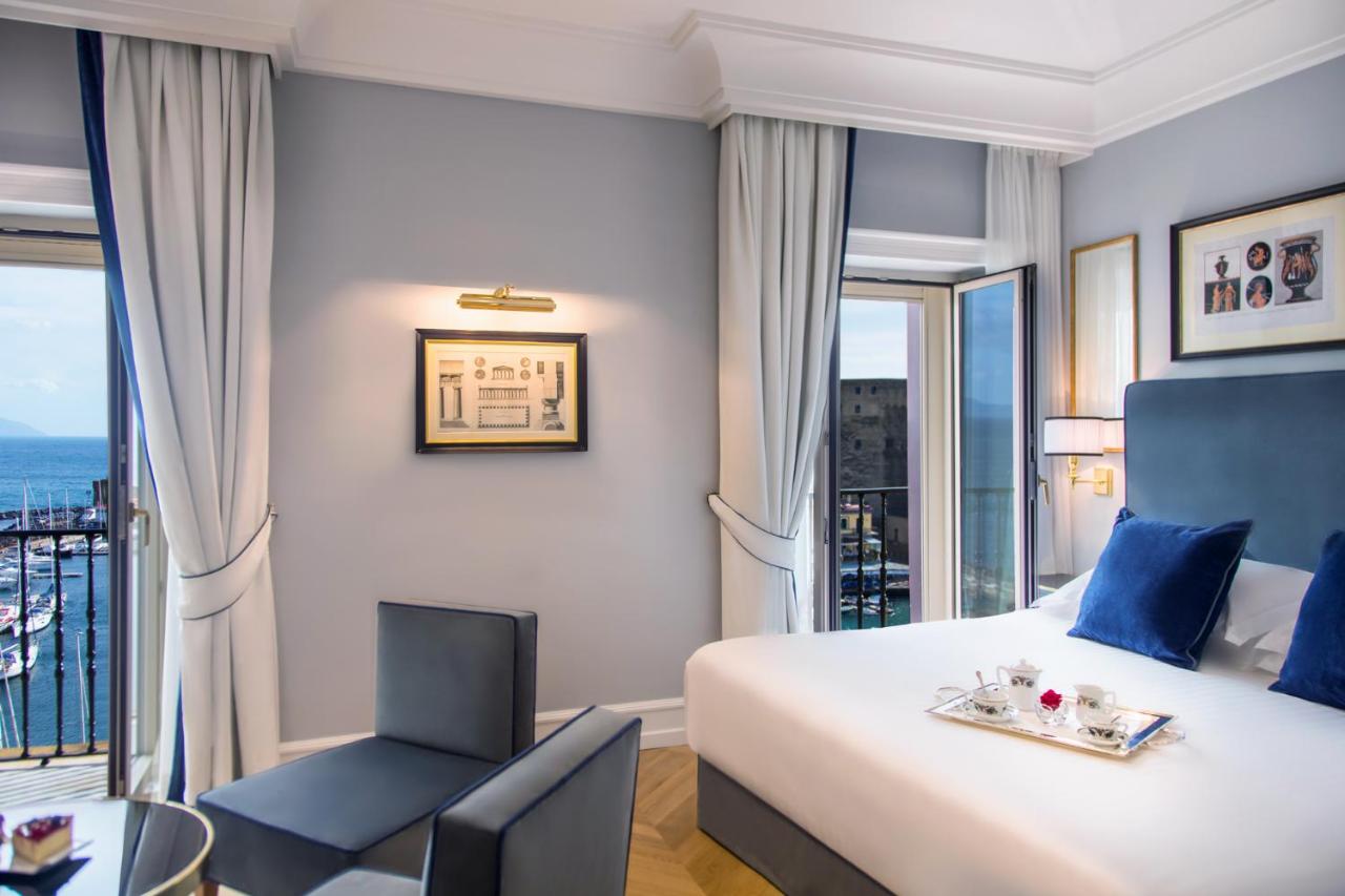 een hotelkamer met een bed en een stoel bij Grand Hotel Santa Lucia in Napels