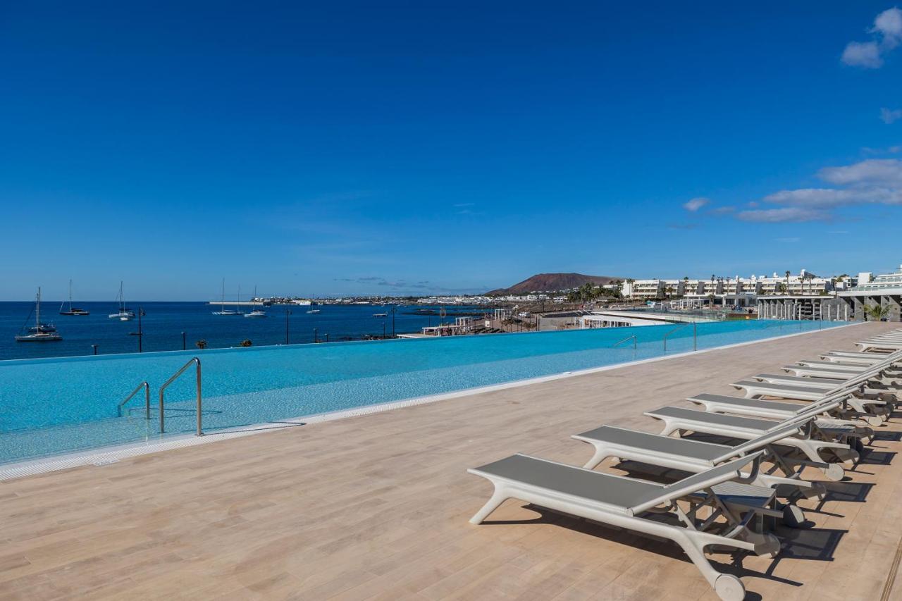 een rij ligstoelen naast een zwembad bij Barceló Playa Blanca Royal Level - Adults Only in Playa Blanca