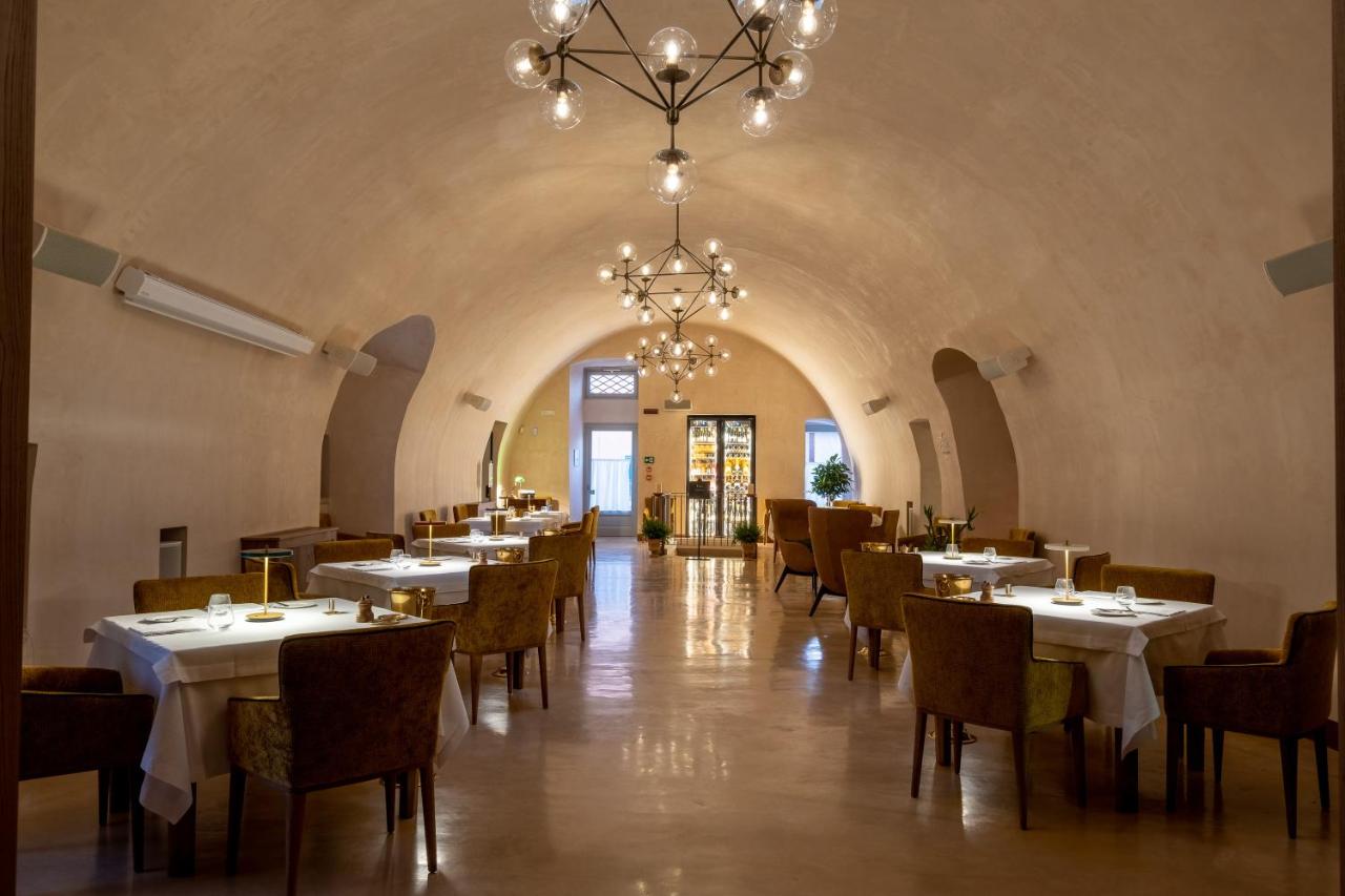 een eetkamer met tafels en stoelen en een kroonluchter bij Nohasi Palace Lifestyle Hotel & SPA in Noha