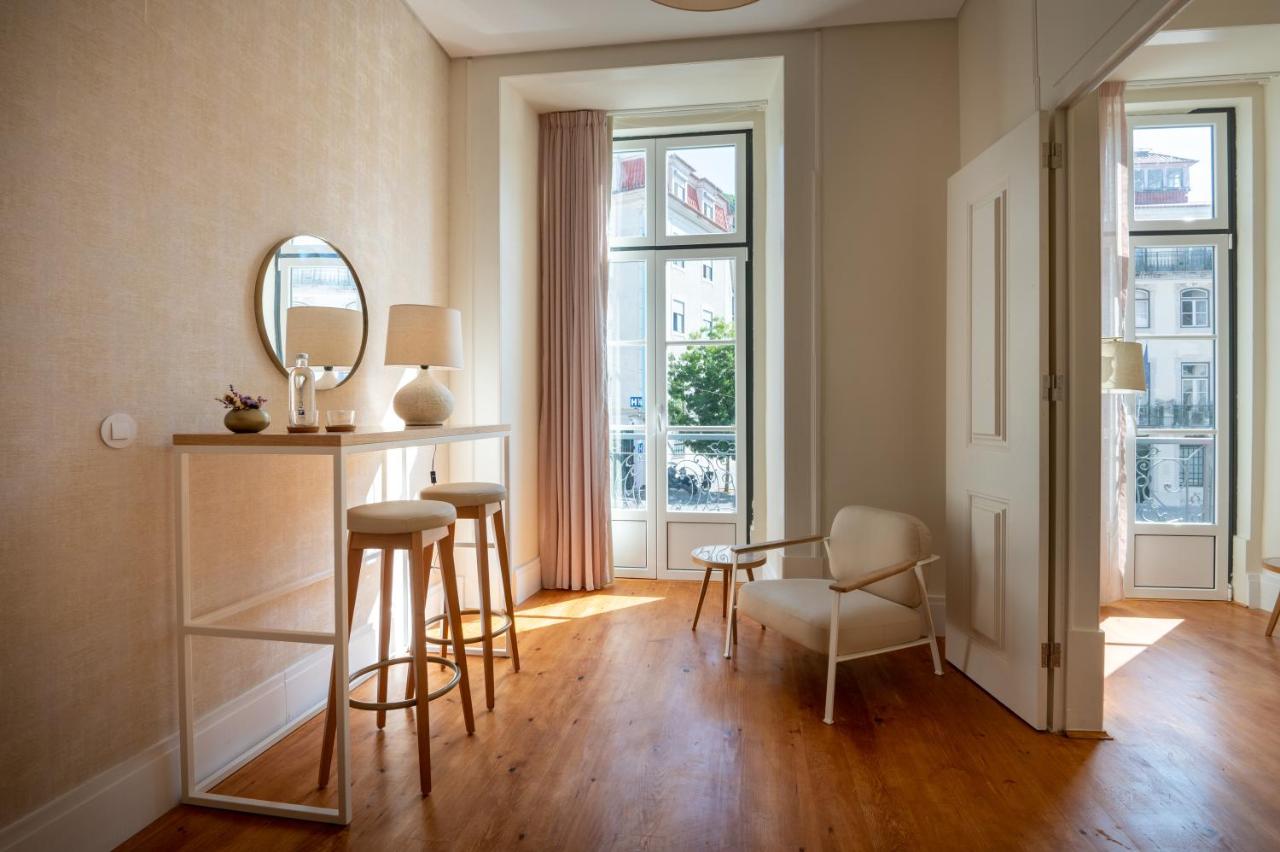 een woonkamer met een tafel en stoelen en een spiegel bij Memoria Lisboa FLH Hotels in Lissabon