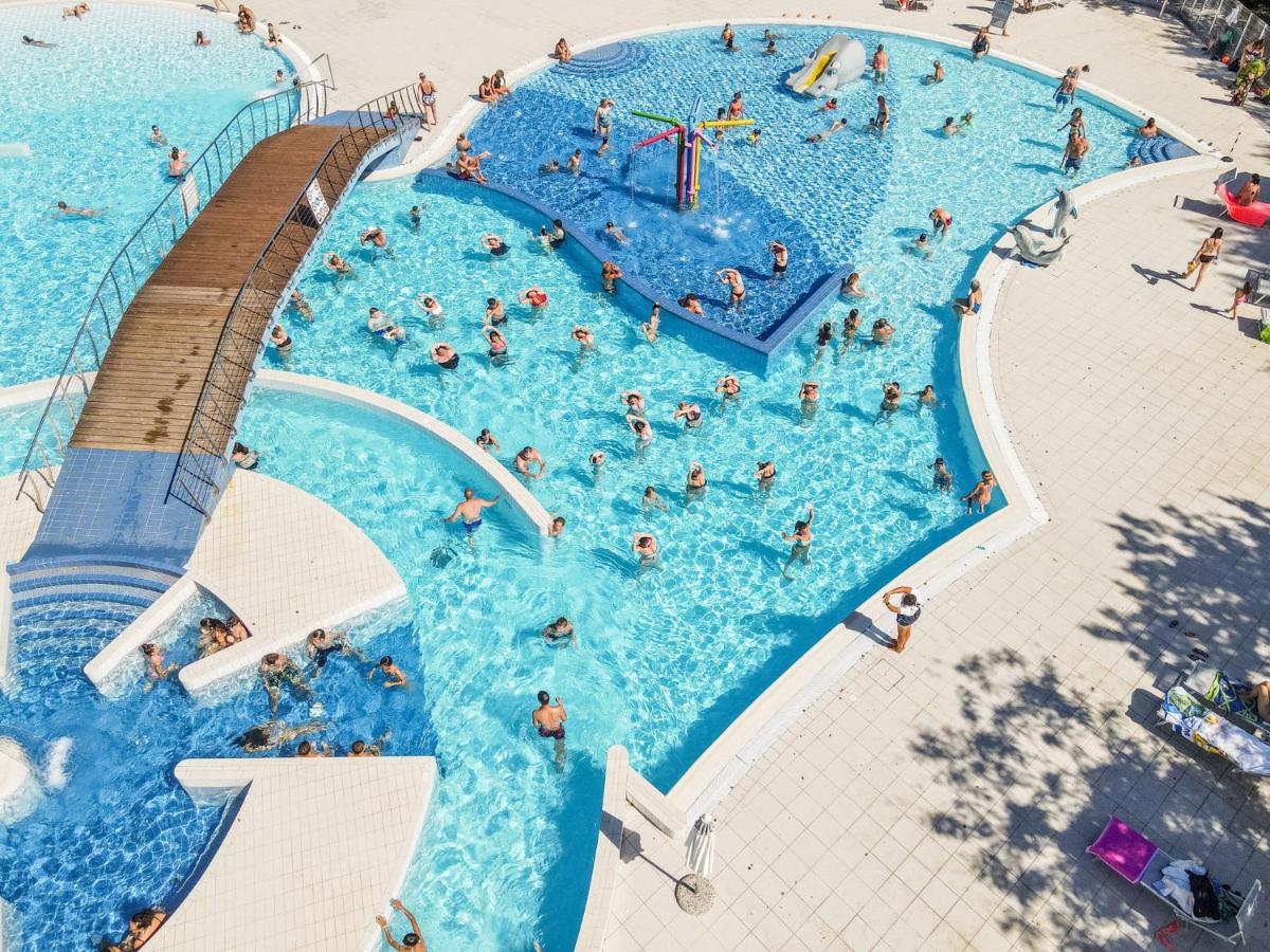 Een bovenaanzicht van een zwembad met mensen erin. bij Club del Sole Adriano Family Collection in Punta Marina