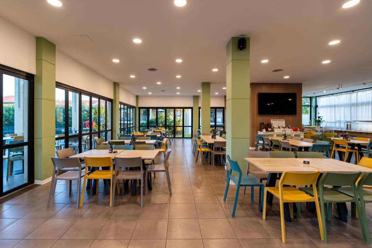 een eetkamer met tafels en stoelen en ramen bij Belvedere Village in Castelnuovo del Garda