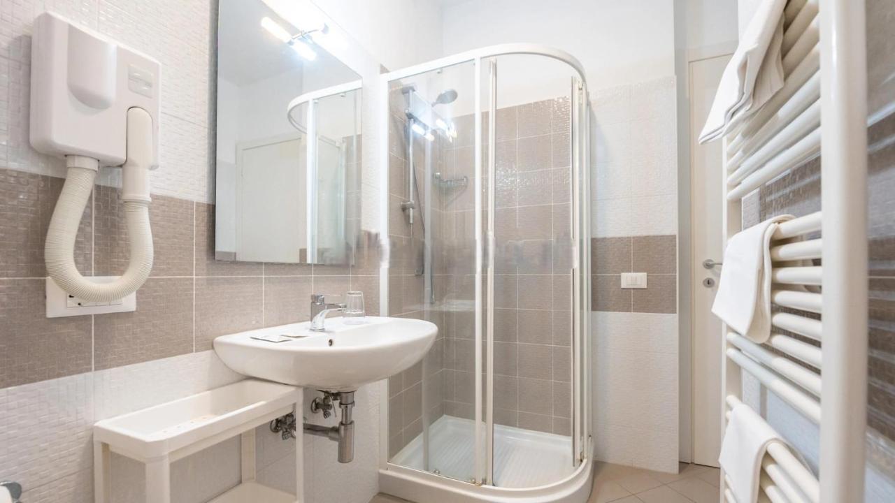 een witte badkamer met een wastafel en een douche bij Nuovo Hotel SettiBi in Giulianova
