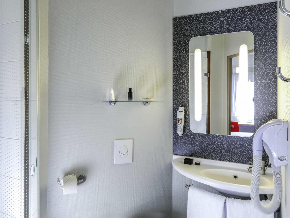 een badkamer met een wastafel en een spiegel bij ibis Orange Sud in Orange