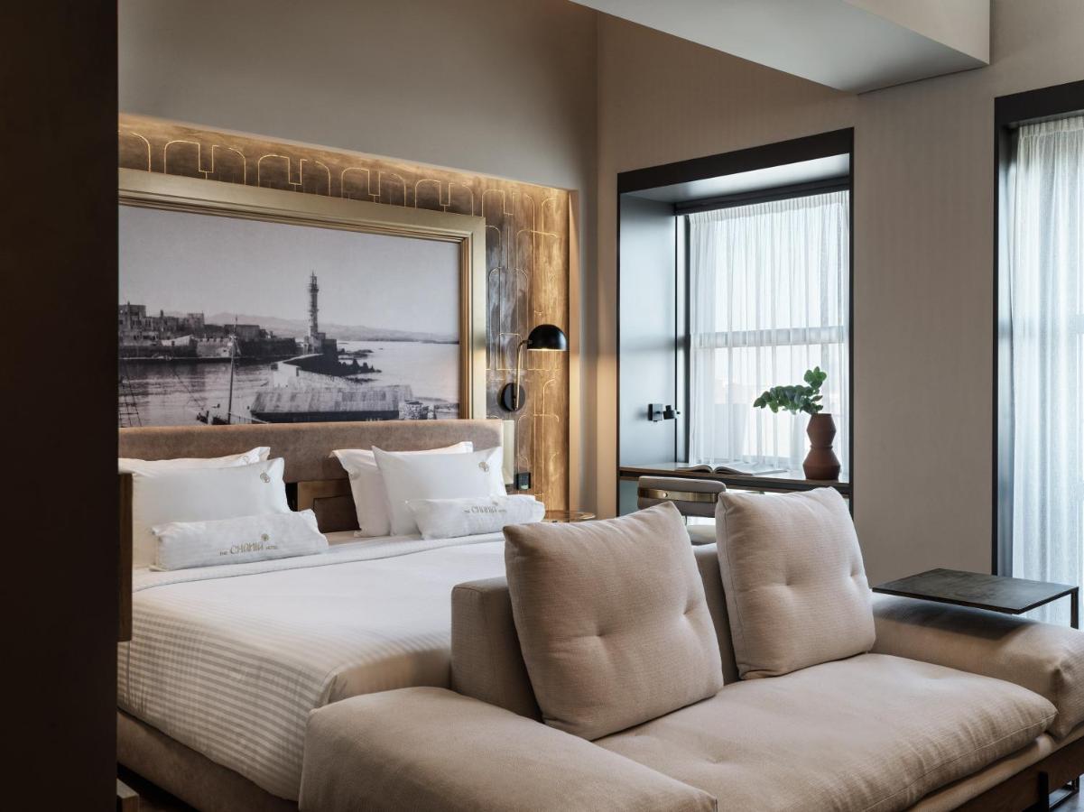 een slaapkamer met een groot bed en een bank bij The Chania Hotel Crete, Vignette Collection in Chania
