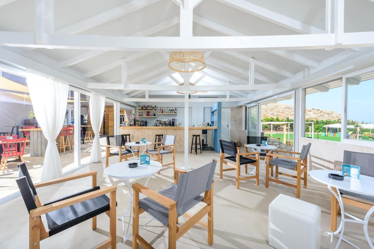 een restaurant met tafels, stoelen en ramen bij Anemos Suites by Estia in Karteros