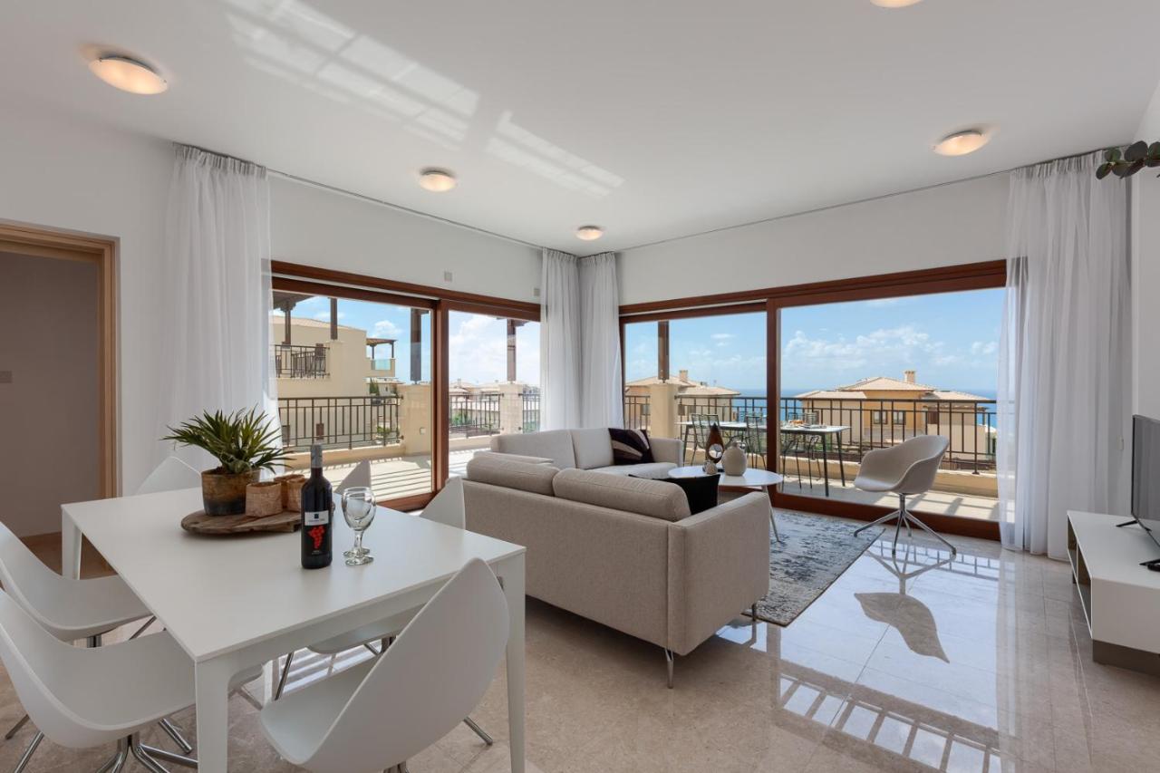 een woonkamer met een bank, een tafel en stoelen bij Aphrodite Hills Rentals - Premium Serviced Apartments in Kouklia