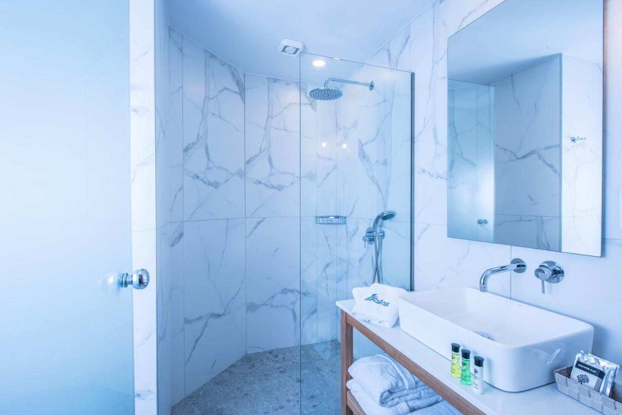 een witte badkamer met een wastafel en een douche bij Aeolos Beach Resort in Malia