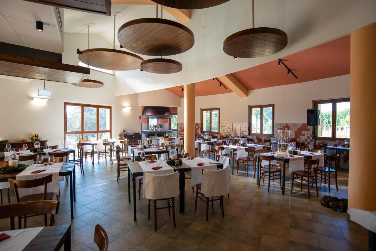 een eetkamer met tafels en stoelen en ramen bij S'ena Hotel in Arbus