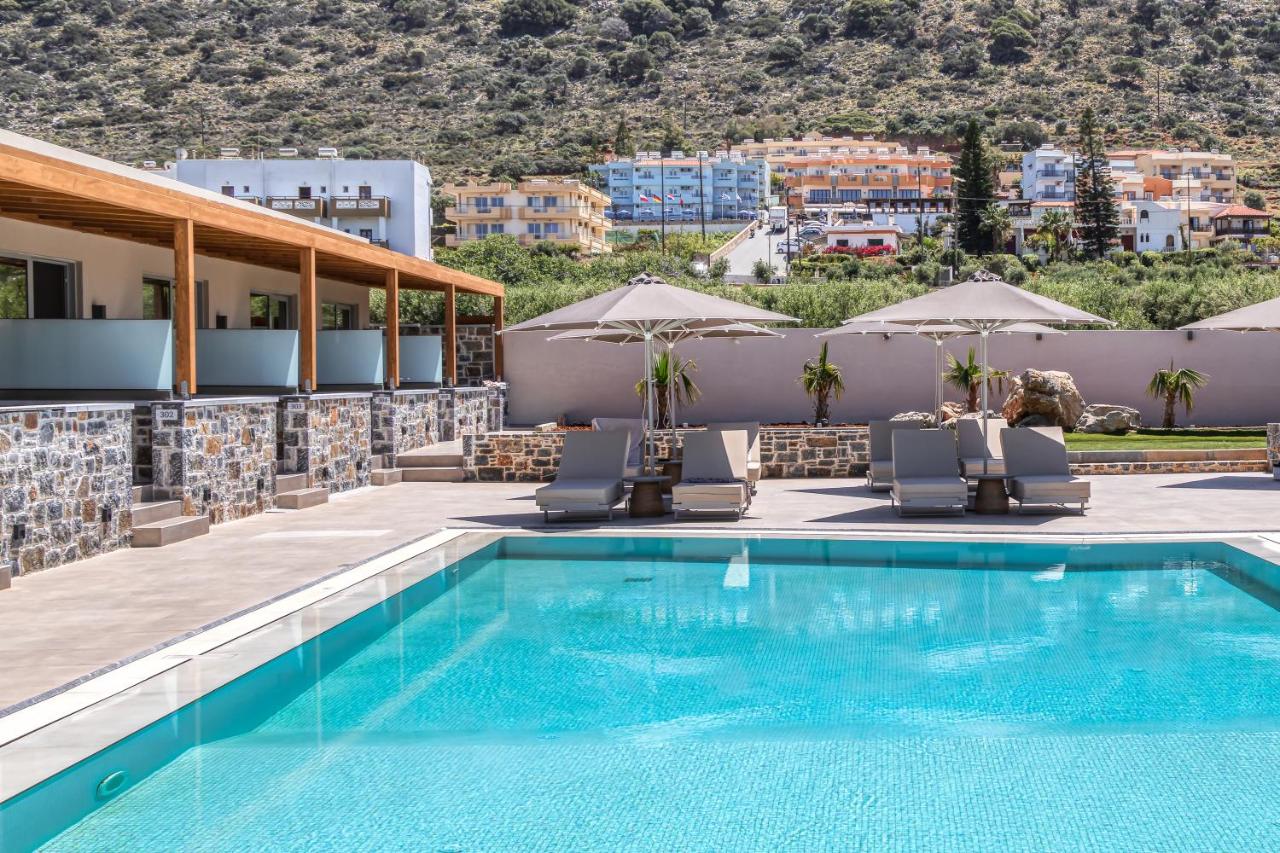een zwembad op het dak van een hotel met ligstoelen en parasols bij Anassa Stalis Luxury Suites by Estia 'Adults Only' i