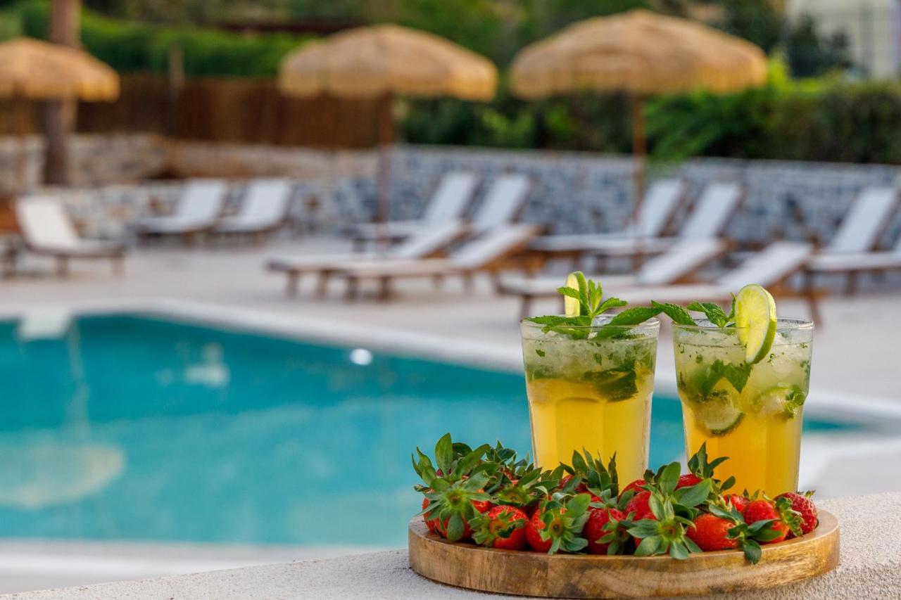 Twee drankjes op een dienblad naast een zwembad. bij Anassa Stalis Luxury Suites by Estia 'Adults Only' in Stalida
