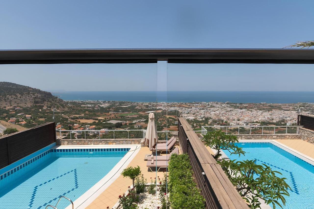 een uitzicht op een zwembad vanuit een gebouw bij The Noverian Scenic Crete 5 Star Hilltop Villa Resort & Spa in Malia