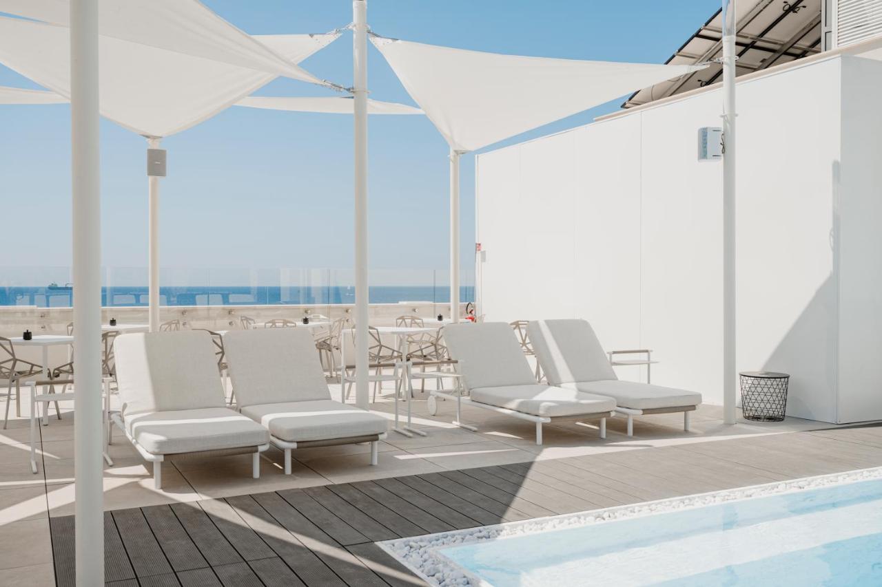 een groep witte stoelen en een zwembad op een dakterras bij Biancodonda Greenblu Hotel & SPA in Gallipoli