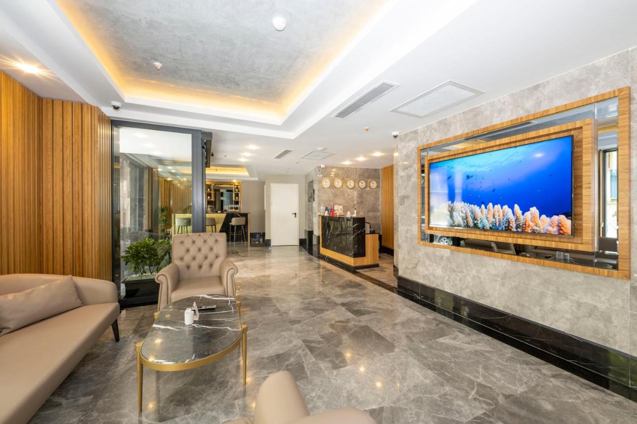 een woonkamer met een bank en een tv aan de muur bij Hotel Ravi in Istanbul
