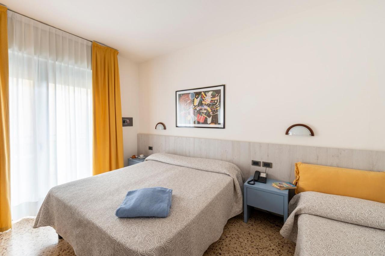 een hotelkamer met twee bedden en een stoel bij Olimpia Hotel & Aparthotel in Bibione