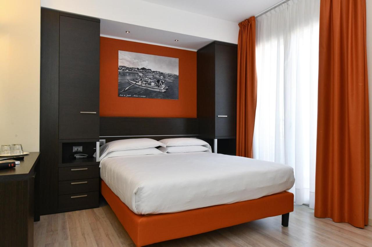 een slaapkamer met een groot bed en een oranje muur bij Hotel Vienna in Lido di Jesolo