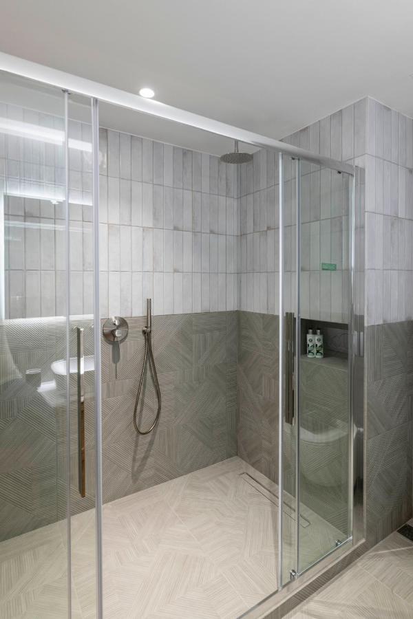 een douche met een glazen omhulsel in een badkamer bij PAREA Athens in Athene