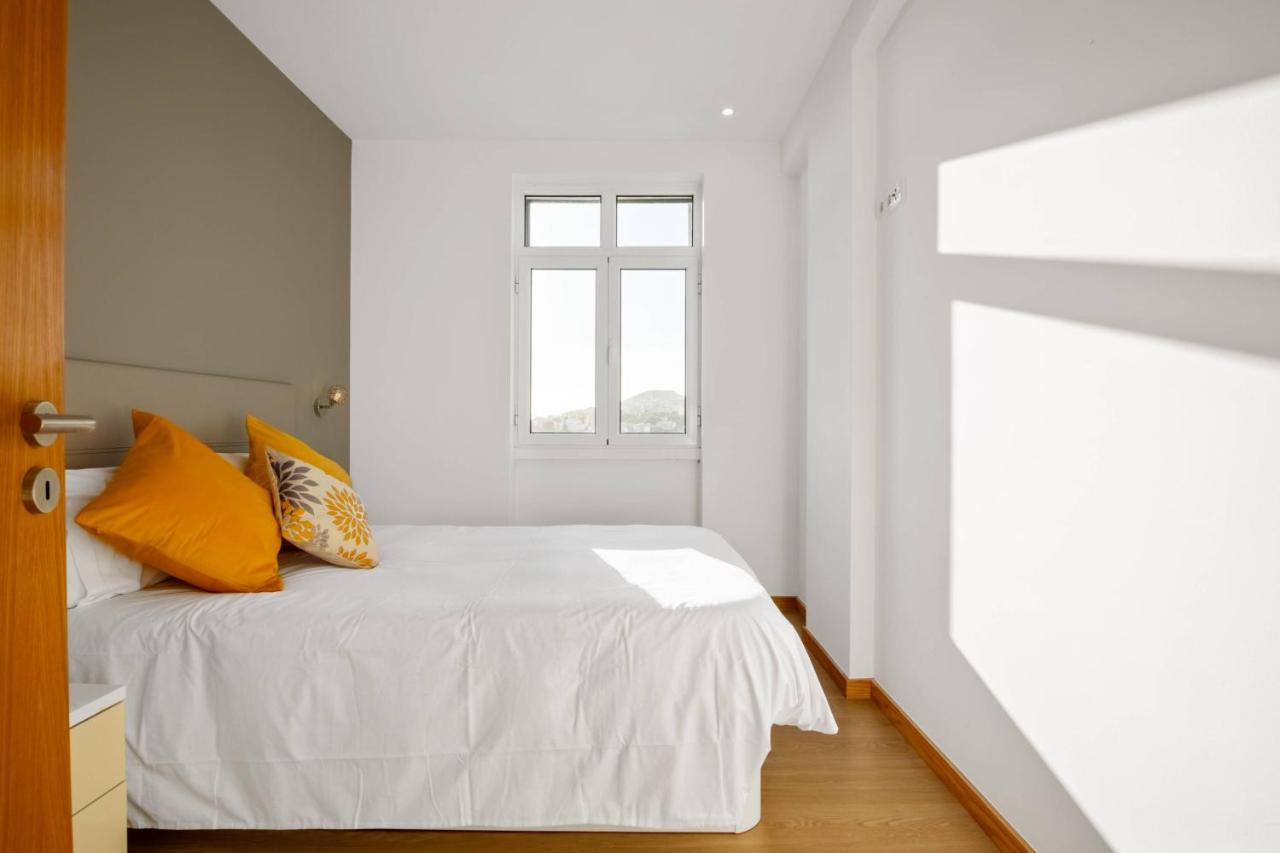 een slaapkamer met een wit bed en oranje kussens bij Apartamento Eden in Funchal