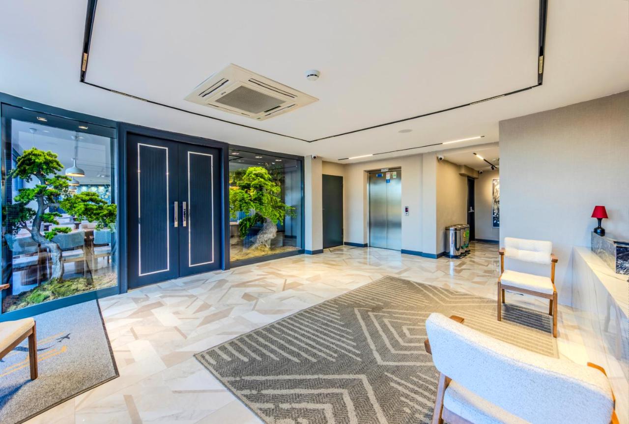 een lobby met stoelen, een tafel en glazen deuren bij Heaven Premium Hotel Restaurant & Airport Shuttle in Arnavutköy