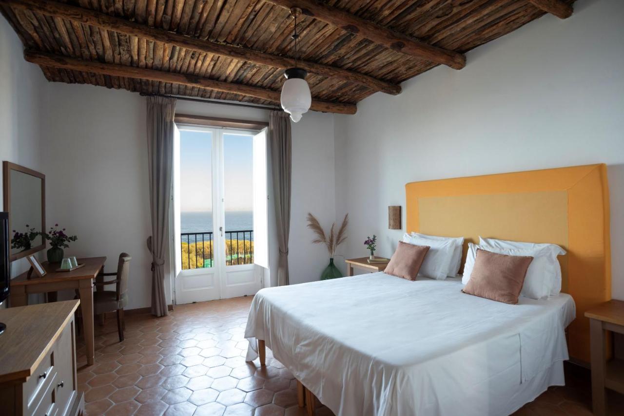 een slaapkamer met een groot bed en een groot raam bij Villa Puolo – With Private Sea Access in Sorrento