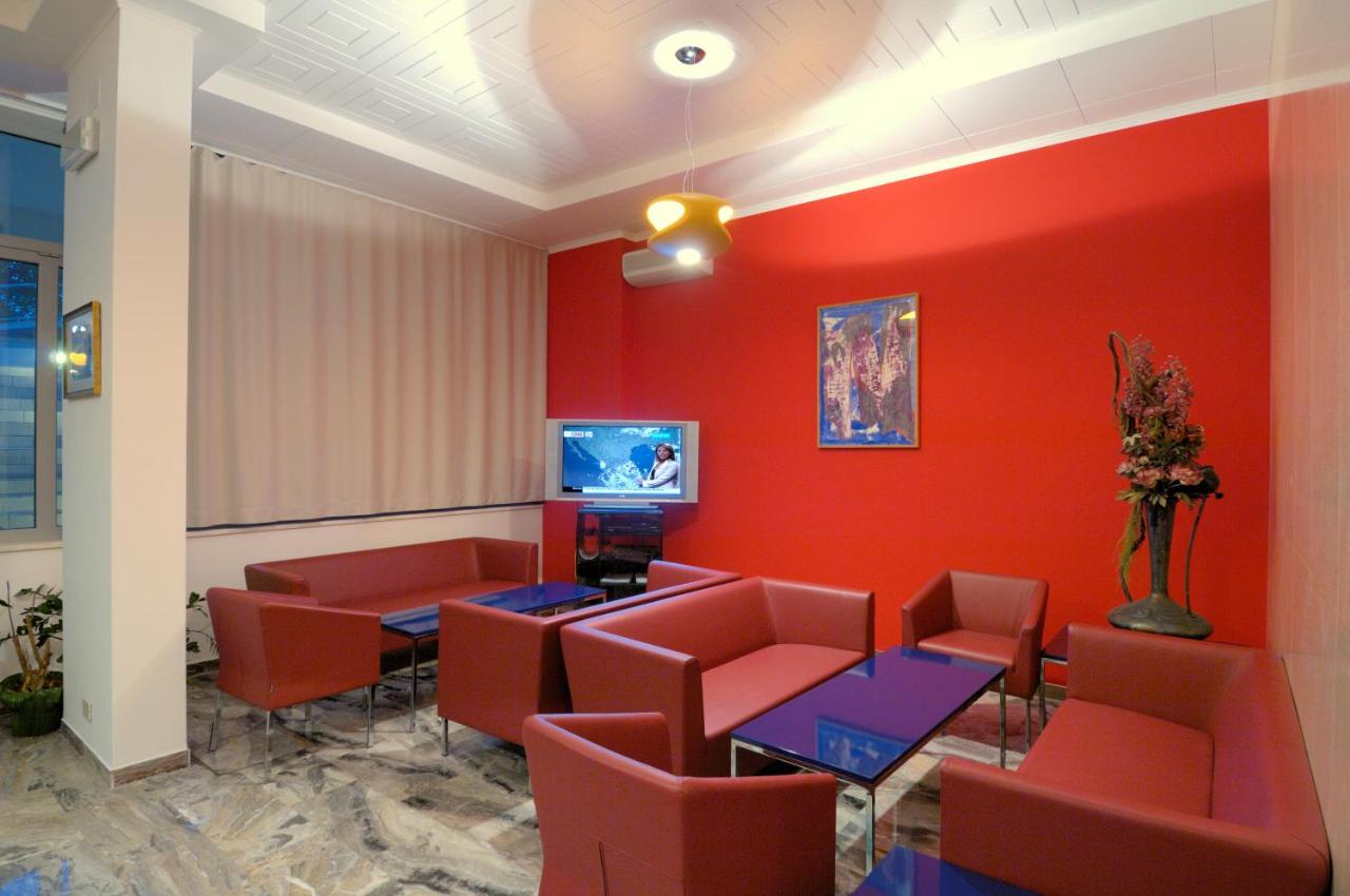 een wachtkamer met rode muren, tafels en stoelen bij Hotel Firenze in Bibione